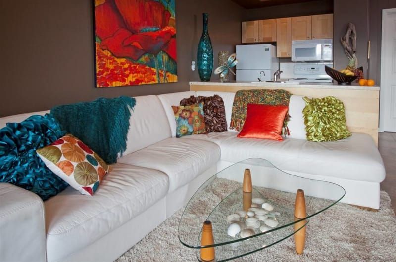 A living room with a white sectional couch and a glass coffee table