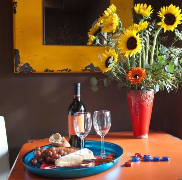 A bottle of wine sits on a table next to a vase of sunflowers