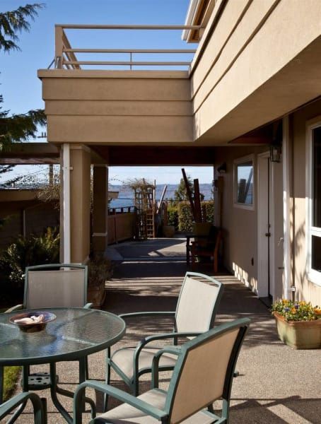 A patio with a table and chairs with a view of the ocean