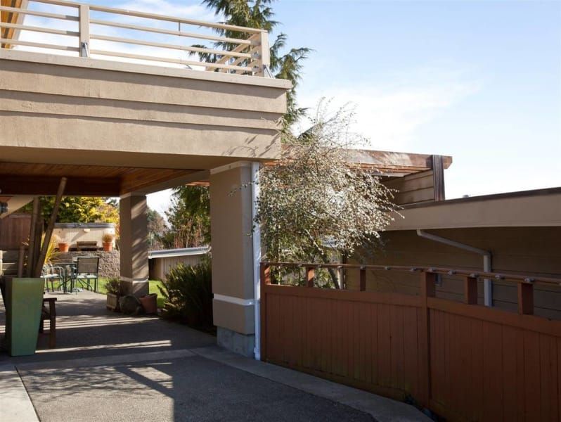 A driveway leading to a house with a wooden fence