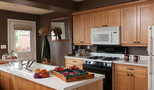 A kitchen with wooden cabinets , a stove , microwave , refrigerator and sink.