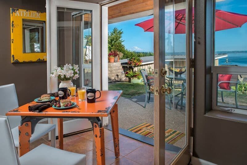 A dining room with a table and chairs and a view of the ocean.