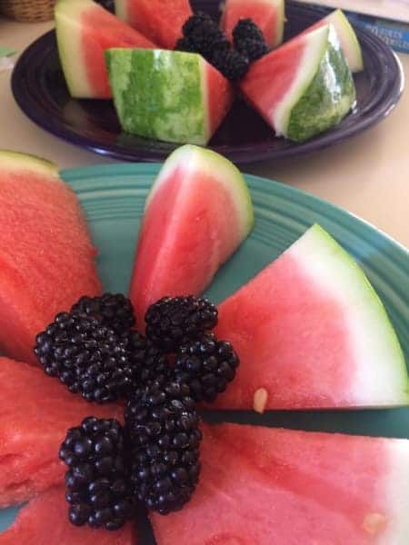 Two plates of watermelon and blackberries on a table