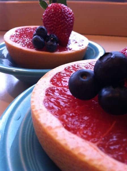 Two slices of grapefruit with strawberries and blueberries on top
