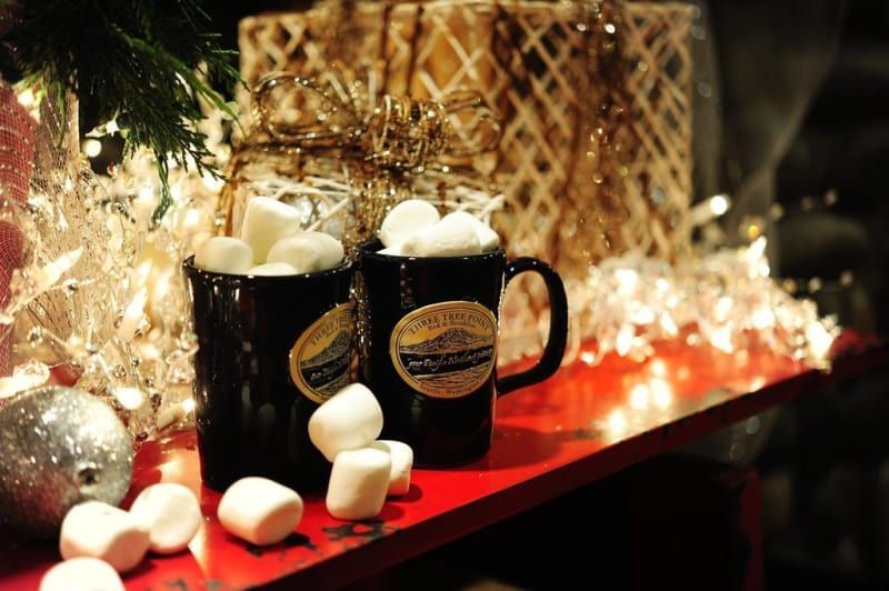 Two mugs filled with hot chocolate and marshmallows on a table