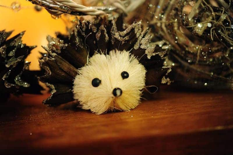 A stuffed hedgehog made out of pine cones is sitting on a wooden table.