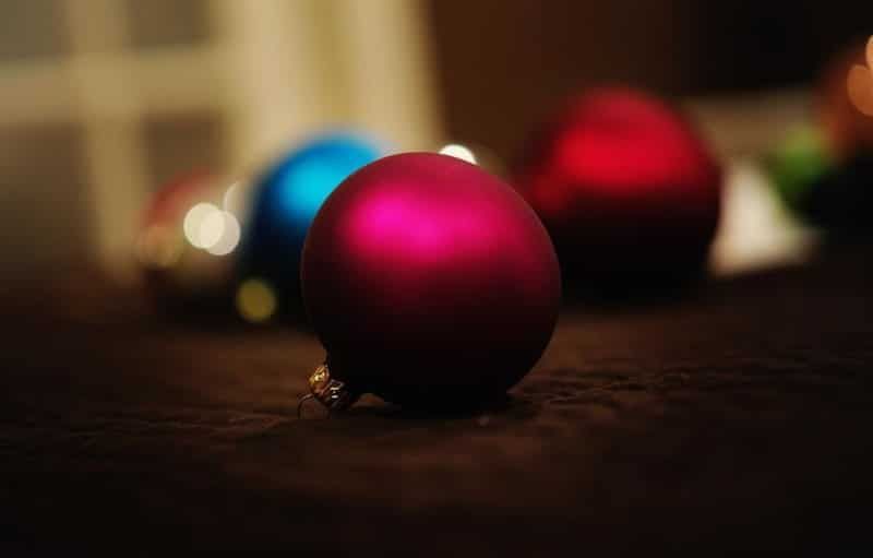 A group of christmas balls are sitting on a wooden table.