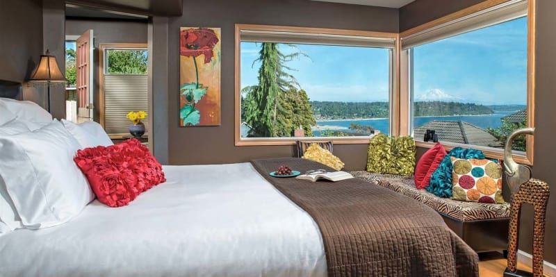 A bedroom with a king size bed and a large window with a view of the ocean.