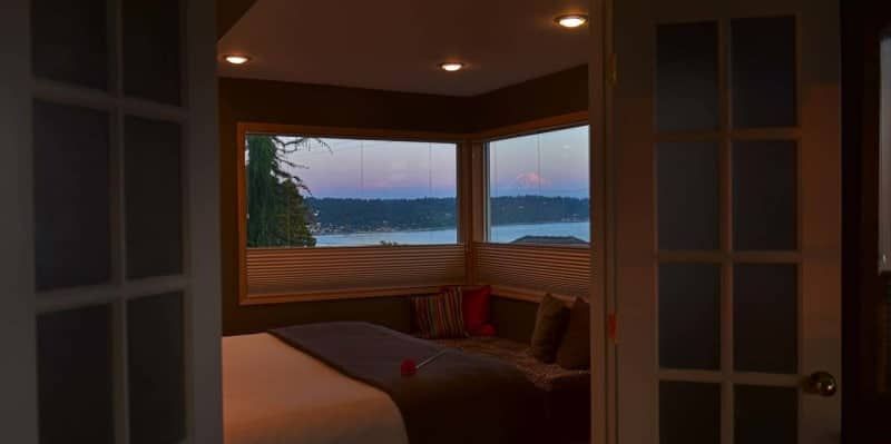A bedroom with a bed and a window overlooking a body of water.