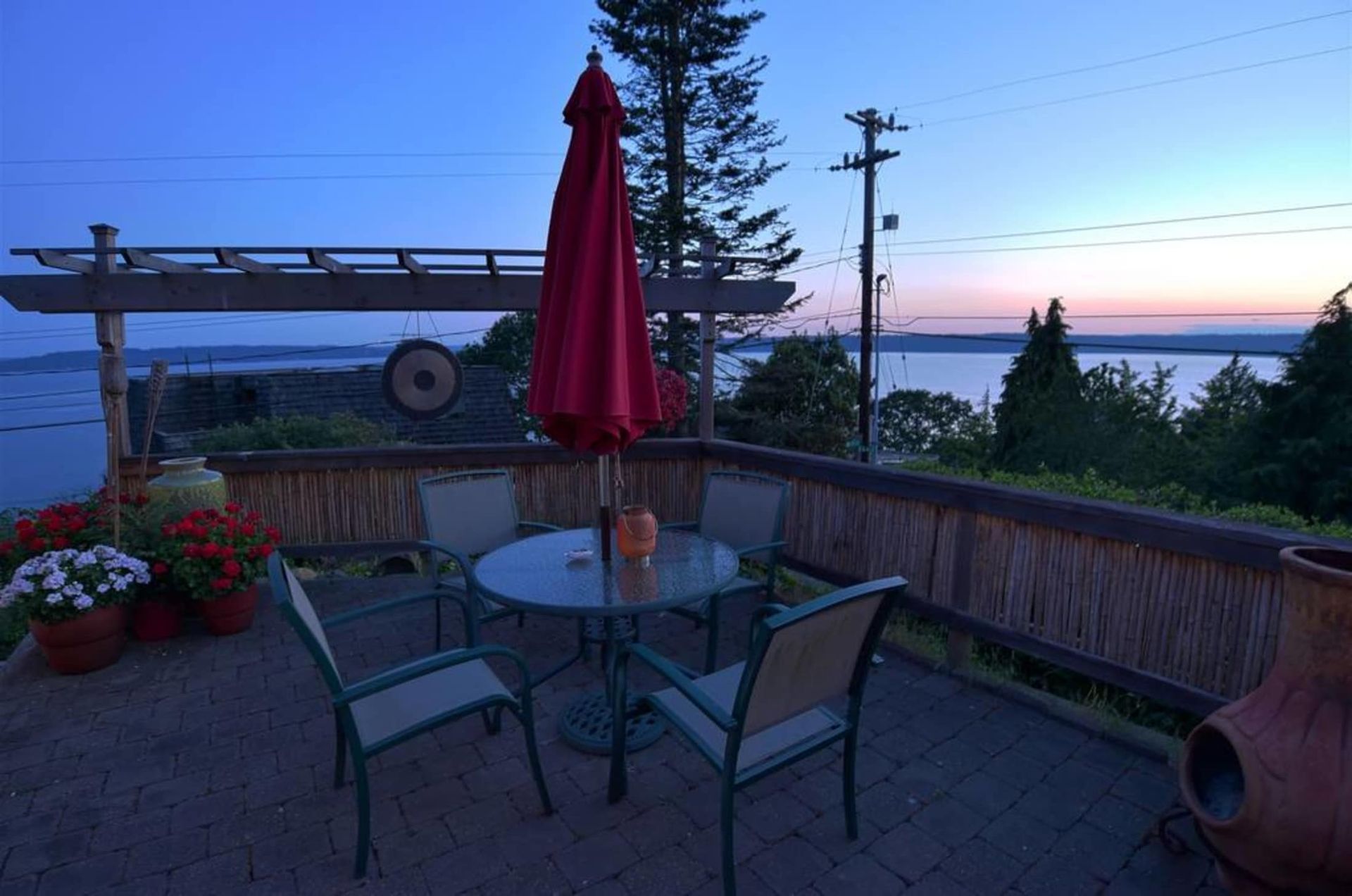 A patio with a table and chairs and an umbrella overlooking a body of water.