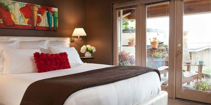 A bedroom with a bed , sliding glass doors and a painting on the wall.
