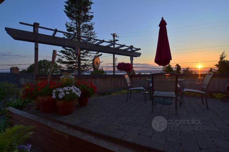 A patio with chairs and an umbrella at sunset
