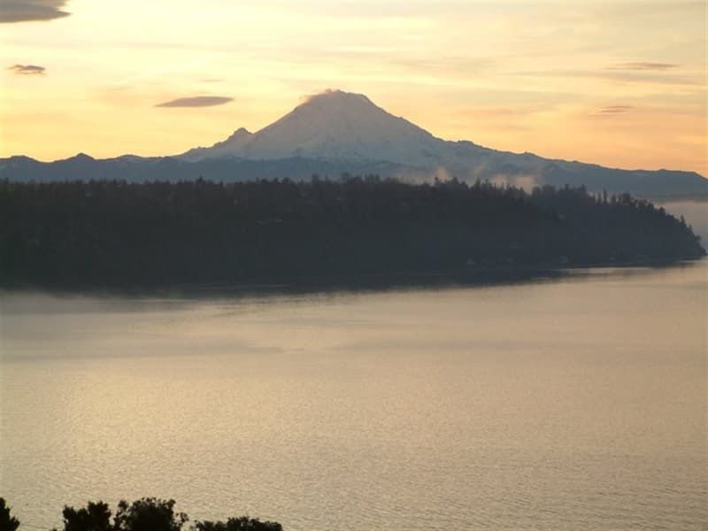 A sunset over a lake with a mountain in the background