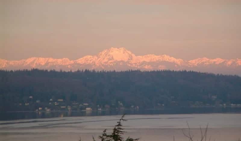A view of a lake with mountains in the background at sunset.