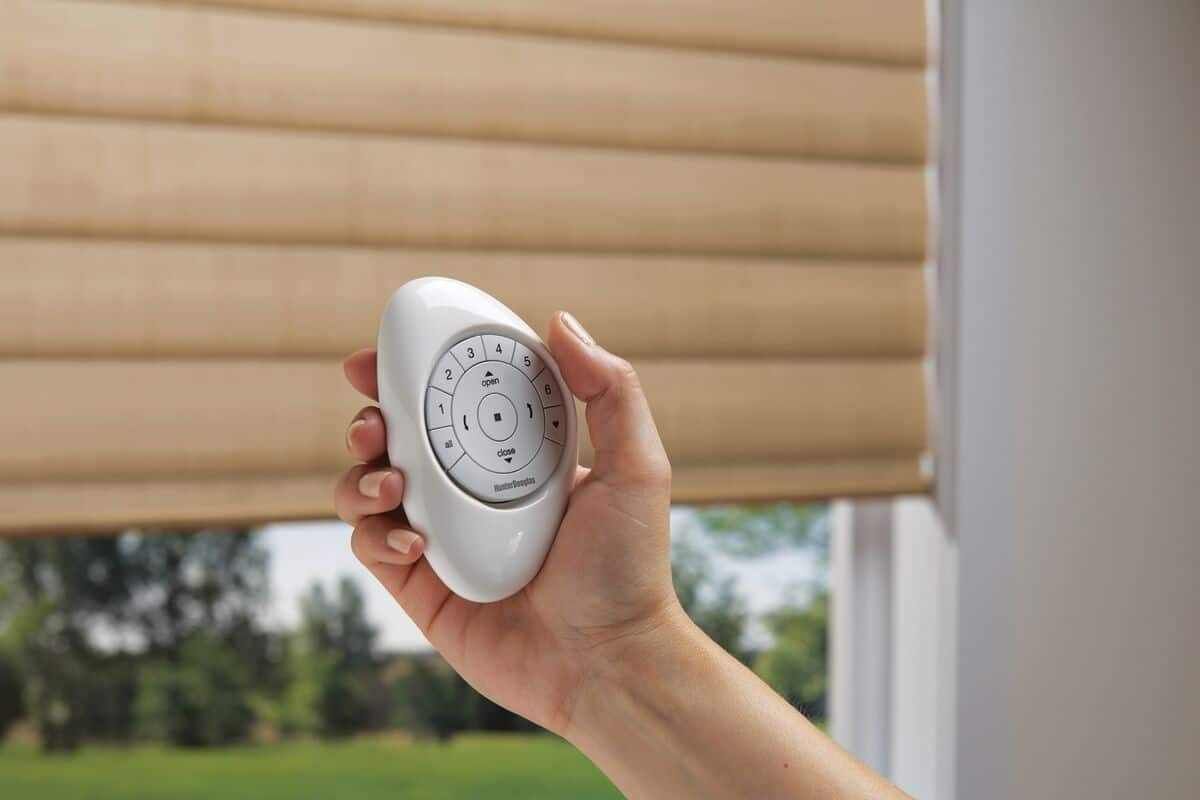Image of a person’s hand using Pebble® Remote to use PowerView® Automation over a shade