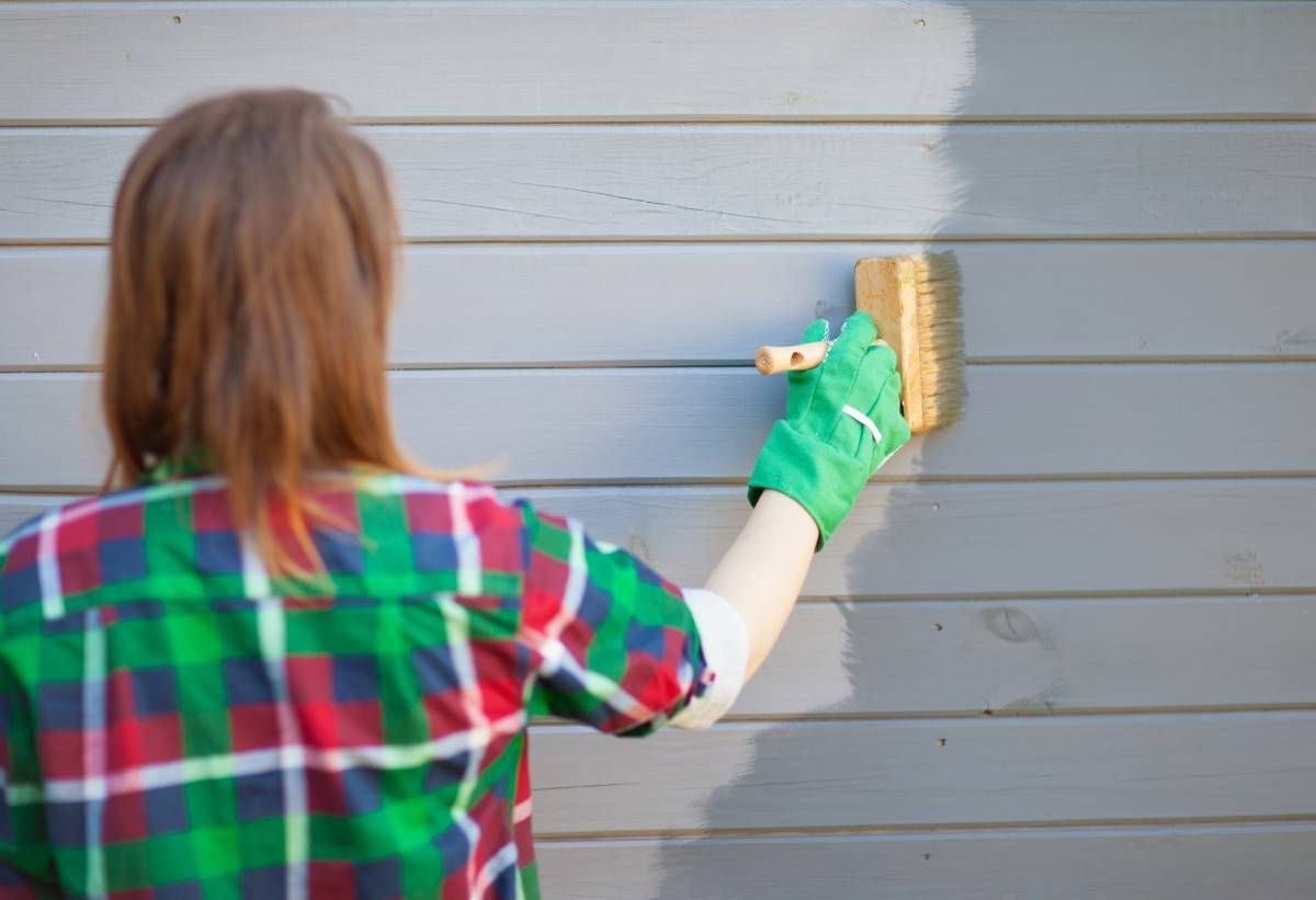 A woman painting her home with Benjamin Moore Regal® Select Exterior Paint near Fort Lauderdale, FL