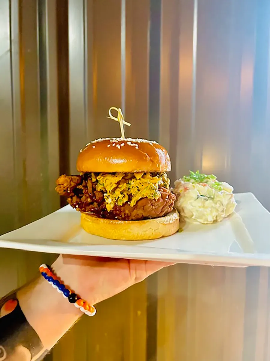 Burger with fries and pickles on a white plate at a restaurant table