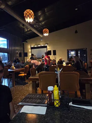 Dim restaurant interior with diners seated at tables and warm hanging lights.