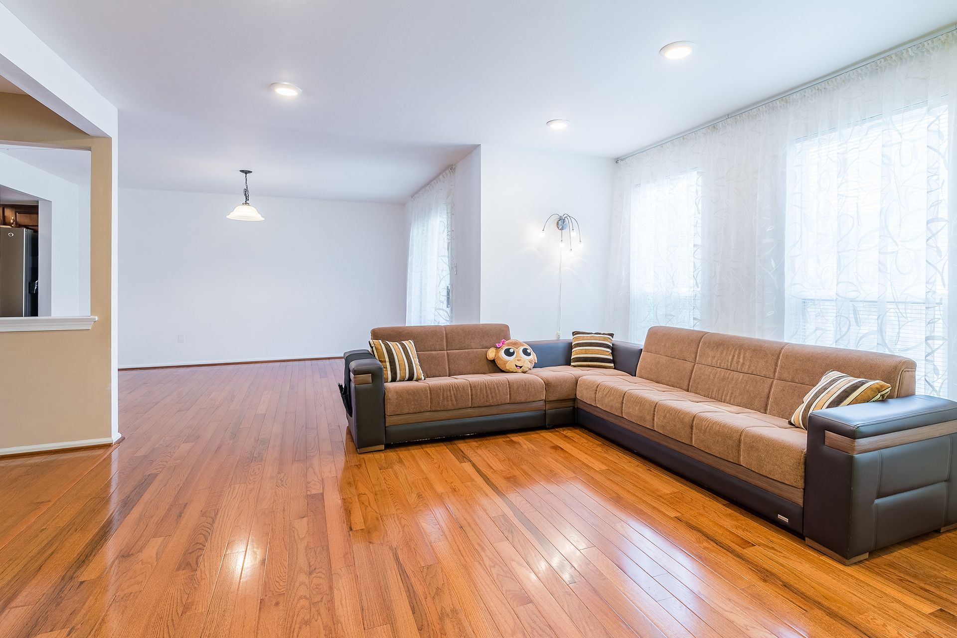 L-shaped sofa in a living room with hardwood floors and sheer curtains. L-shaped sofa in a living room with hardwood floors and sheer curtains.