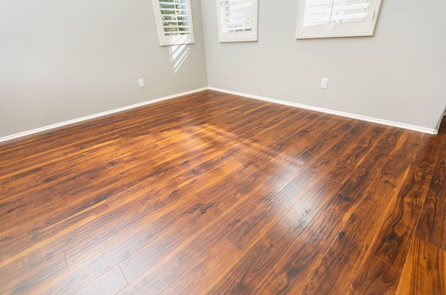Empty room with dark wood flooring, gray walls, and three windows with closed shutters. Empty room with dark wood flooring, gray walls, and three windows with closed shutters.