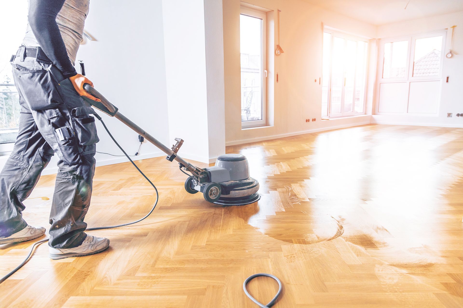 Person uses floor buffer on a wooden floor in a sunlit room. Person uses floor buffer on a wooden floor in a sunlit room.