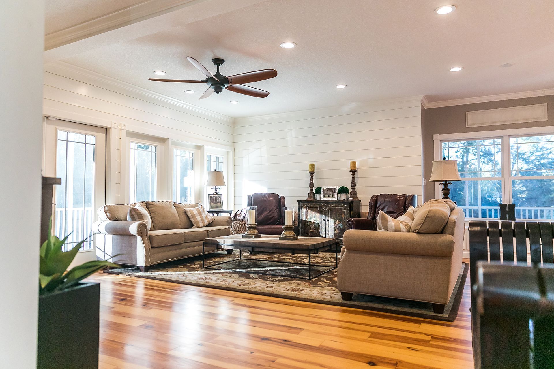Spacious living room with light-colored furniture, hardwood floors, and large windows. Spacious living room with light-colored furniture, hardwood floors, and large windows.