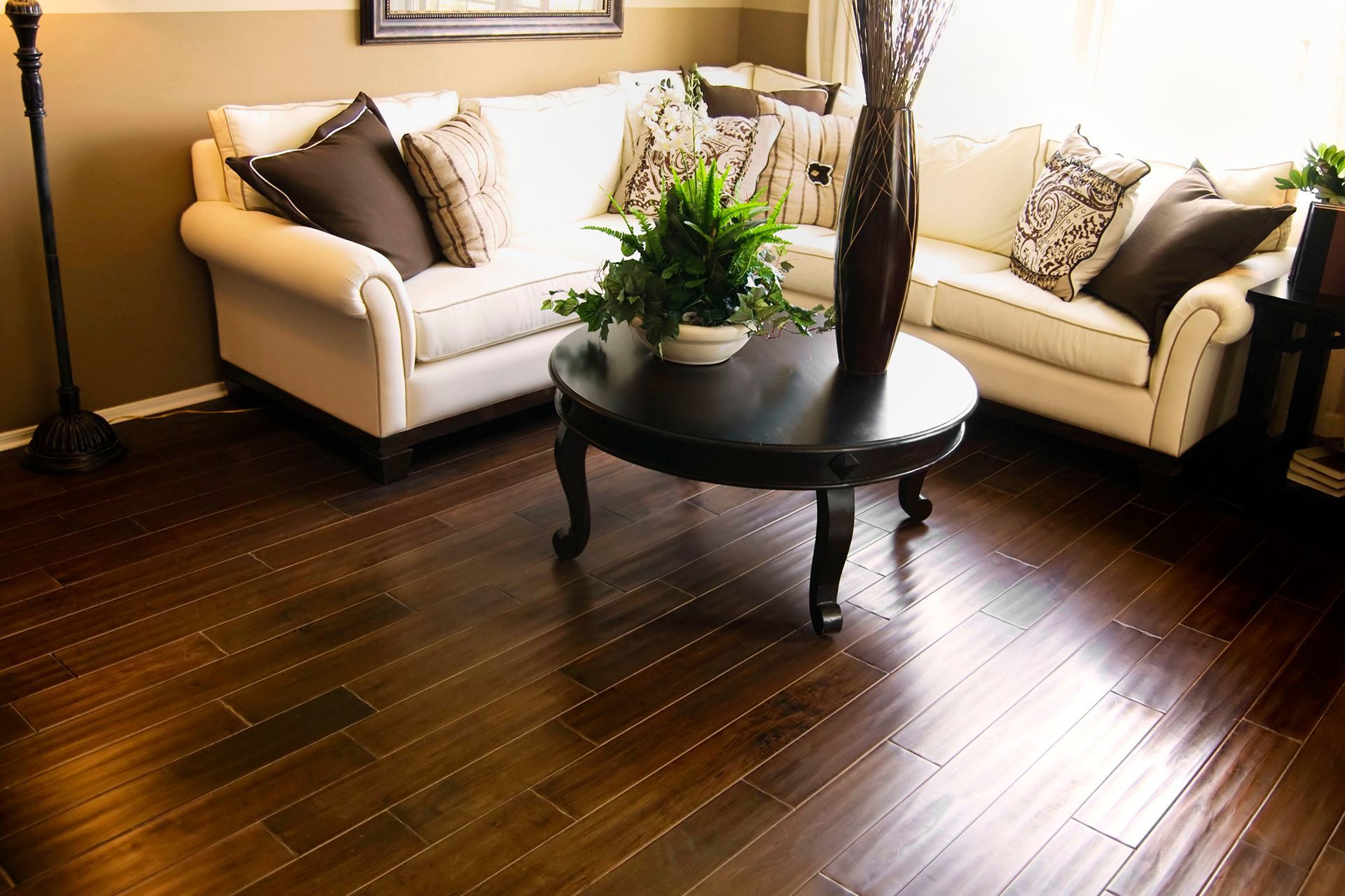 Living room with dark wood floors, white sofa, coffee table, and tall vase. Living room with dark wood floors, white sofa, coffee table, and tall vase.