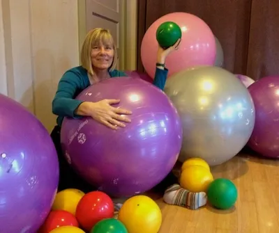 A woman is hugging a large purple exercise ball