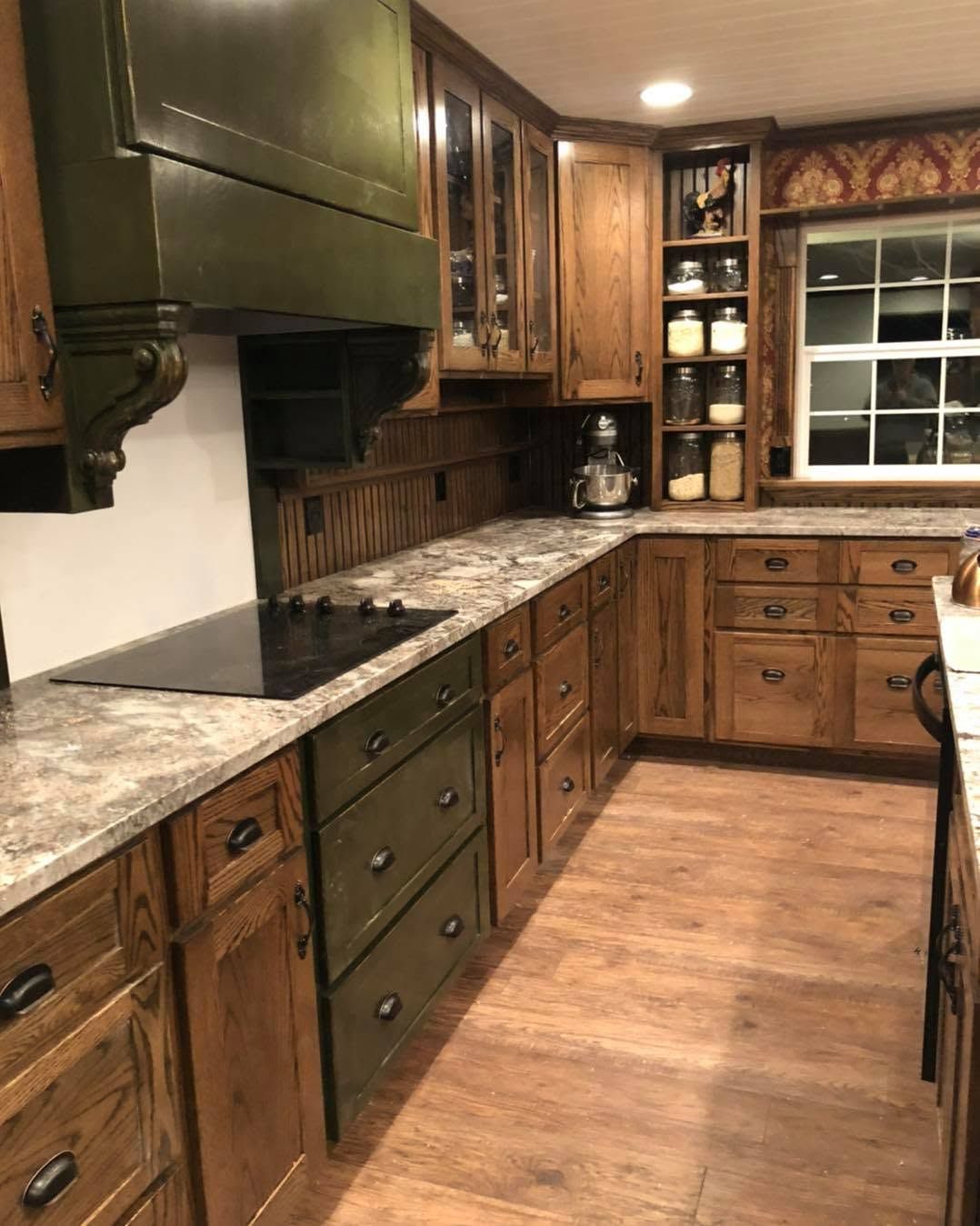 Wooden kitchen with green cabinets, granite countertops, and a window over the sink.
