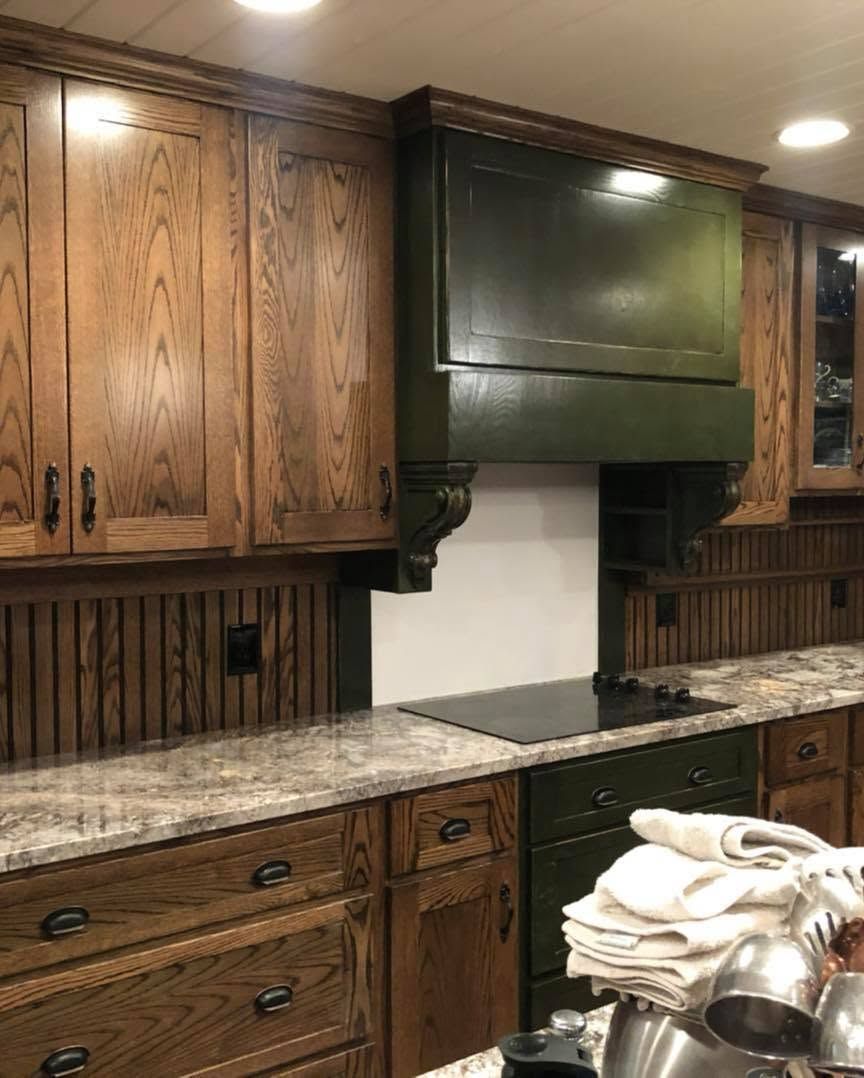 Kitchen with wood cabinets, green range hood, granite countertop, and folded towels near a stovetop