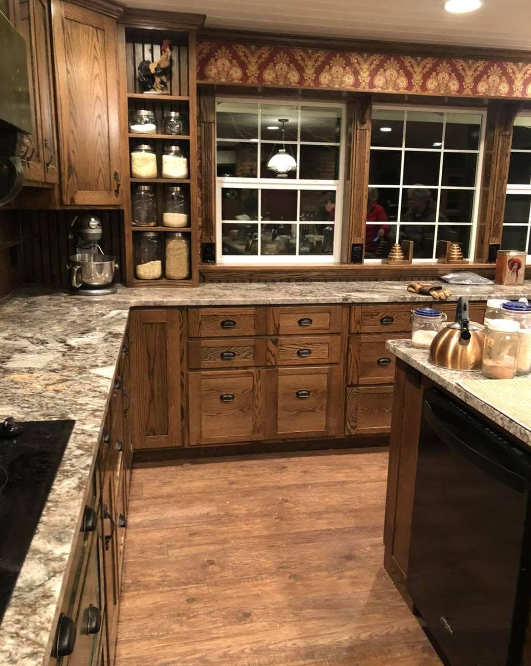 Warm kitchen with wood cabinets, granite counters, and a large window over the sink.