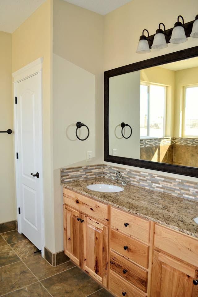 Bathroom vanity with granite countertop, large mirror, and wall sconce above a wooden cabinet.