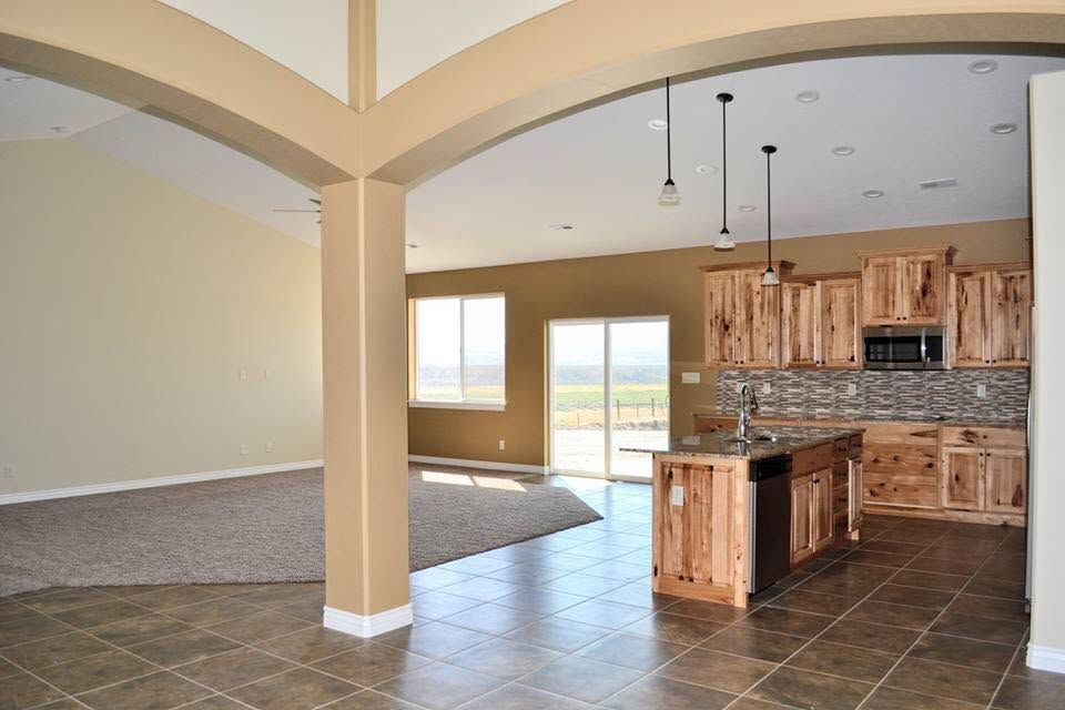 Open-concept kitchen and living room with tile floors, wood cabinets, and a central island