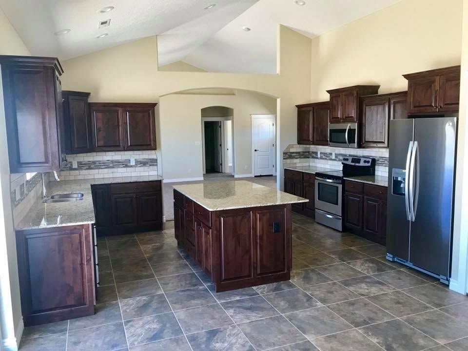 Spacious kitchen with dark wood cabinets, stainless appliances, and a large central island with granite countertop
