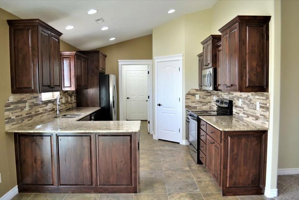Modern kitchen with dark wood cabinets, granite countertops, and tiled floor, viewed from the center