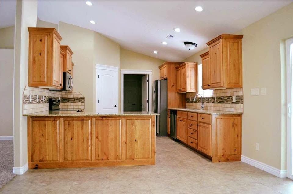 Bright kitchen with wooden cabinets, beige countertops, and tiled floor under recessed lights
