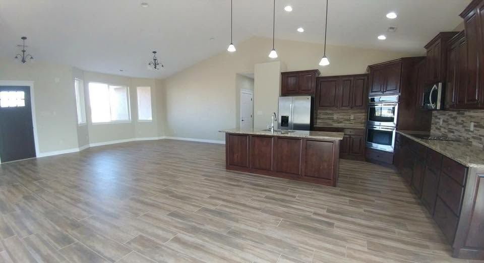 Open-concept kitchen and living area with dark wood cabinets, island, and wood-look flooring