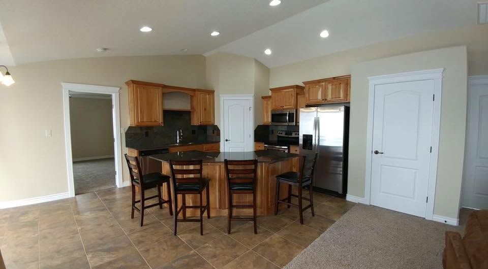Kitchen and dining area with wood cabinets, island bar stools, stainless fridge, and tiled floor