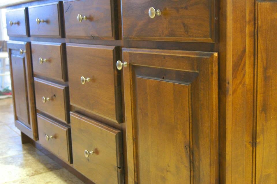 Wooden kitchen cabinet with multiple drawers and brass knobs in a warm-toned room