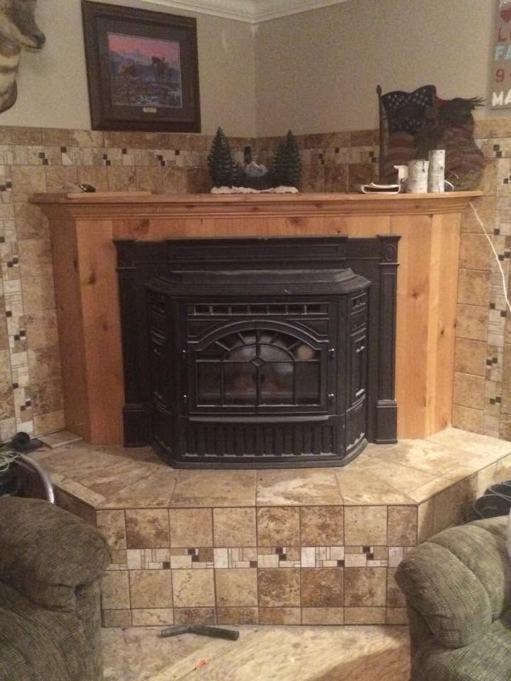 Living room fireplace with black wood stove insert, stone hearth, and log mantel built into a corner alcove