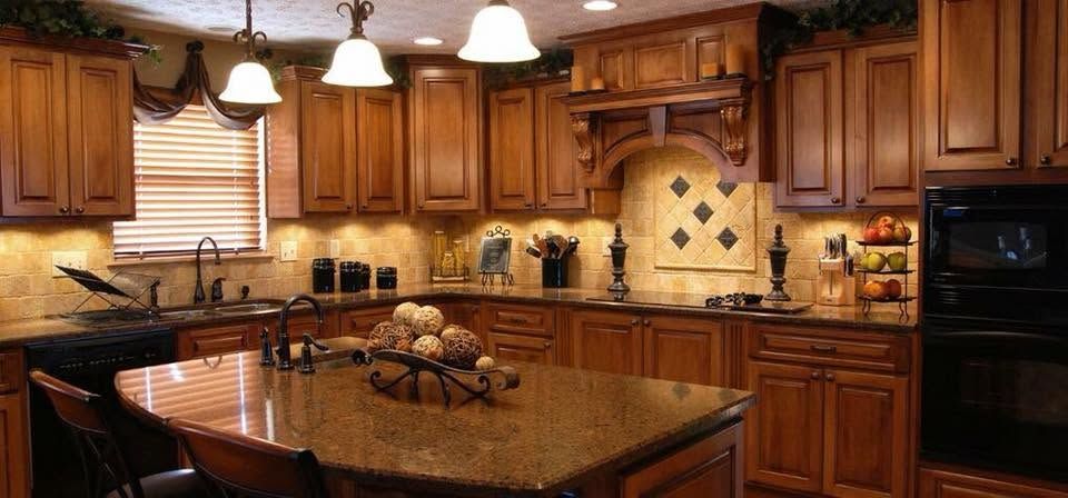 Warm wood kitchen with granite island, hanging pendant lights, and black appliances