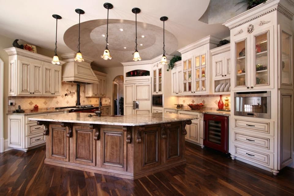 Elegant gourmet kitchen with large island, cream cabinets, dark wood floors, and pendant lights