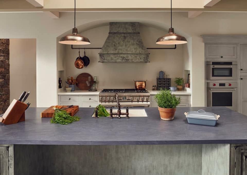 Modern kitchen with large island, pendant lights, and stainless steel range hood