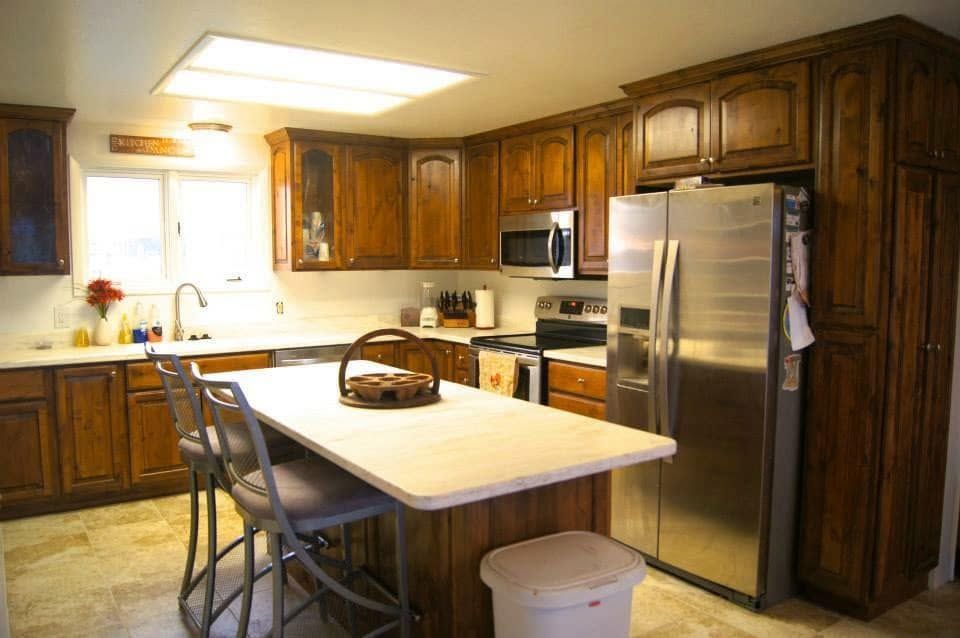 Modern kitchen with wood cabinets, stainless fridge, center island, and bar stools