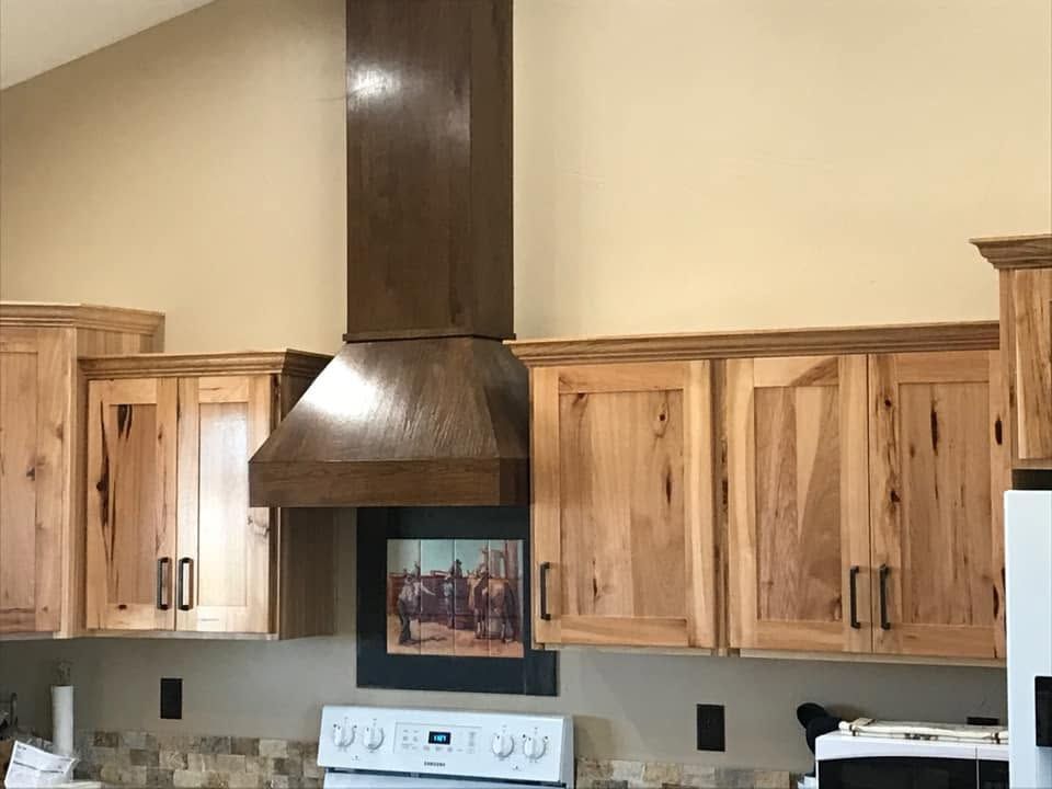 Kitchen with light wood cabinets, stainless range hood, and beige walls.
