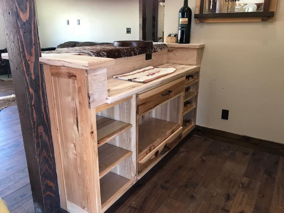 Wooden kitchen island with open shelves and butcher-block top in a room with dark wood floors