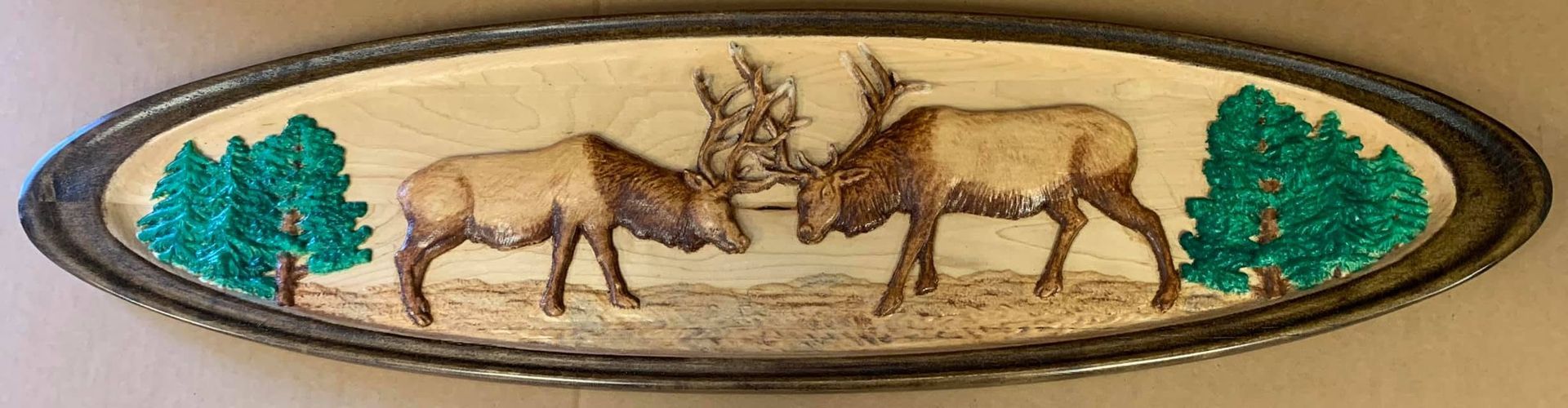 Oval decorative plaque with two deer facing each other between green trees