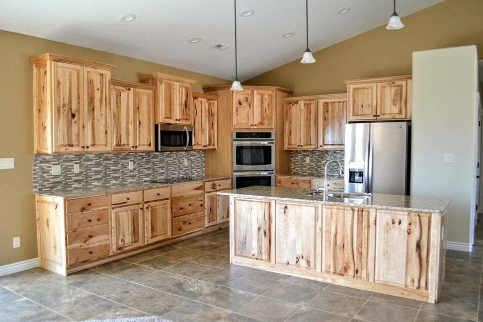 Spacious modern kitchen with light wood cabinets, stainless steel appliances, island, and tiled floor