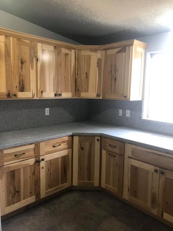 Wooden kitchen cabinets with gray countertops and a bright window in the corner