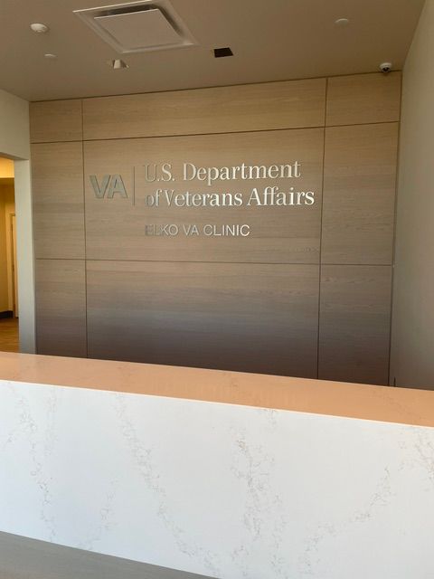 VA Department of Veterans Affairs clinic sign on a beige wall behind a white marble counter.